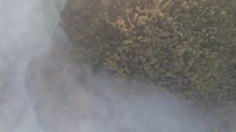 Drone flying through clouds over forest at sunrise, cinematic alpine landscape Stock Footage 325023807