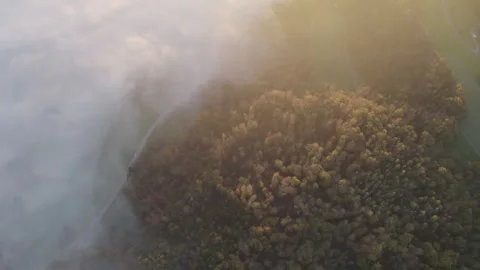 Drone flying through clouds over forest at sunrise, cinematic alpine landscape Stock Footage 325024499