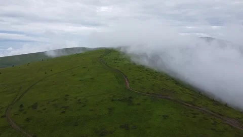 Drone flying through low clouds over green mountains Stock Footage 336631612