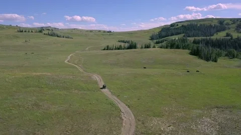Drone flying through mountain valley as ATV rides on dirt road Stock Footage 132229031