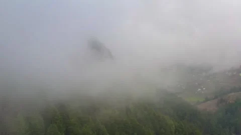 Drone flying through thick clouds over green pine forest to reveal a mounta.. 库存影片 338150518