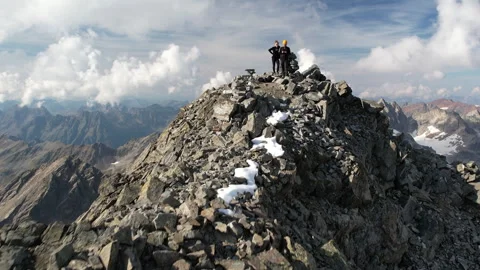 Drone flying toward and over mountaineers on a mountain peak Video stock 325328818