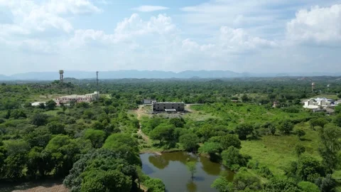 Drone flying toward under-construction building in lush rural landscape Stock Footage 310487685