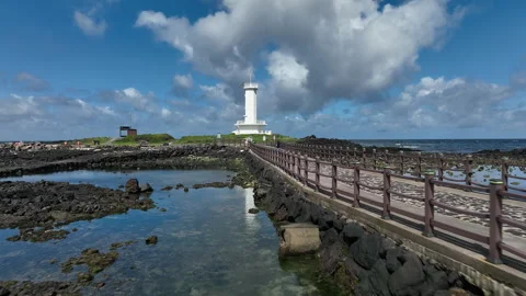 Drone flying toward white lighthouse on Jeju island coast in South Korea Vidéo 348319329