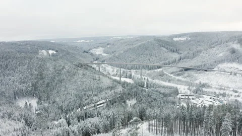 Drone flying towards long highway bridge over snowy forest valley with cars Stock-Footage 332010835