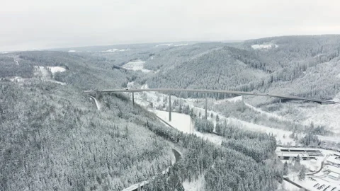Drone flying towards long highway bridge over snowy forest valley with cars Video stock 332011798