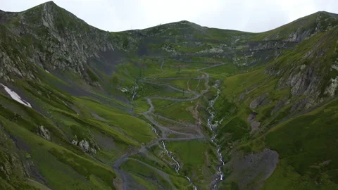 Drone flying towards to peak of mountain above rocky river and serpentine road Stock Footage 229859187