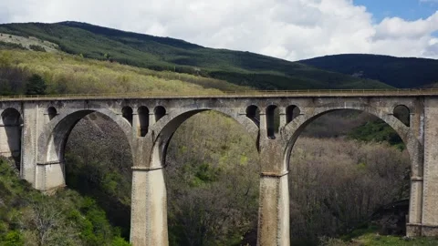 Drone flying towards stone viaduct over a green mountain valley in Gascones, Stock Footage 337705618