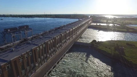 Drone flying towards sun setting over hydroelectric power dam creating swirl Stock Footage 92862974