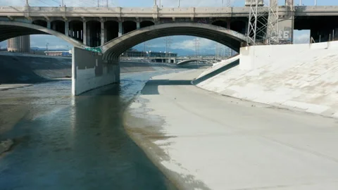 Drone flying under arched concrete bridge above scenic Los Angeles River water 스톡 동영상 185236103