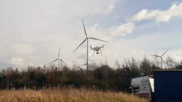 Drone flying off to work on Wind turbine farm renewable energy jobs  Stock Footage 85775599