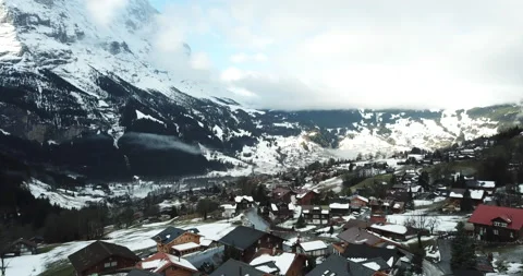 Drone flyover alpine town with snow topped mountains and chalets Stock Footage 140280036
