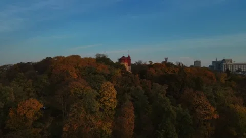 Drone flyover of autumn forest canopy and puppet theatre tower in Kyiv Video stock 346500924