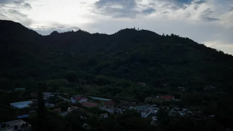 Drone Flyover of Compact Hamlet Tucked Below Forested Mountain Rise Video stock 316797836