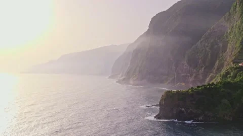 Drone flyover ocean and coastline misty sunrise mountains Seixal beach Madeira Stock Footage 202212330
