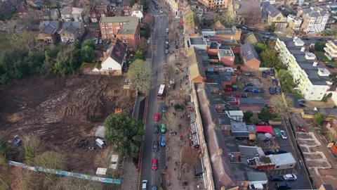 Drone flyover Wanstead High Street with traffic, bus, and cleared plot Vídeos de archivo 327788906