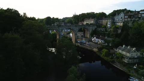 Drone flys in front of waterfront trees next to the river nidd to reveal a Video stock 321440237