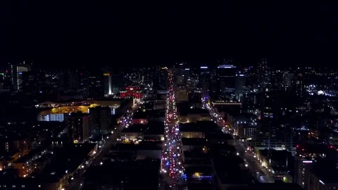 Drone flys over city skyline at night. camera pans down towards street Stock Footage 71134879