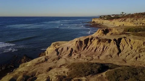 Drone flys over ocean along cliffs during golden hour 스톡 동영상 71133516