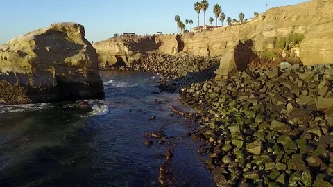 Drone flys over the ocean besides the cliffs during golden hour Stock Footage 71133456