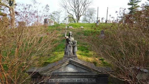 Drone flys to statue atop gothic mausoleum Greenwood graveyard Stock Footage 129274180