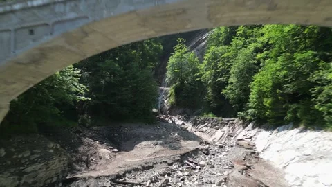 Drone flythrough under bridge towards a mountain waterfall Switzerland Stock Footage 322030092