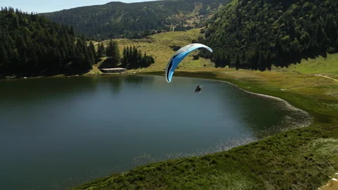 Drone Following a Man Flying Powered Paraglider Over a Beautiful Mountain Lake Stock Footage 270214726