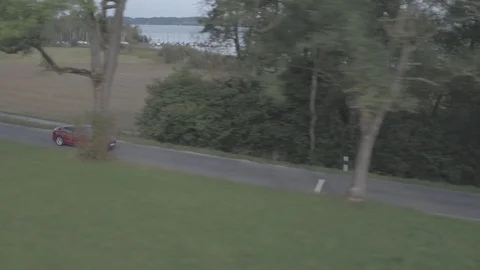 Drone following red Tesla in front of lake Stock Footage 74697169