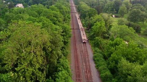 Drone Following Train Moving Down Railroad Tracks in Scenic Landscape Stock Footage 313947451