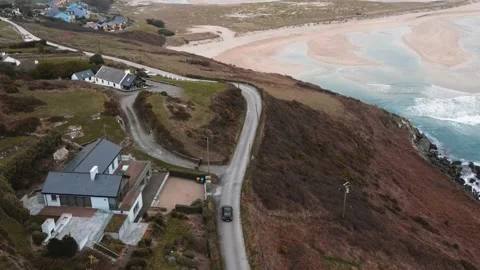 A drone follows a car driving down the road along the Barley Cove beach in Mizen Stock Footage 233196847