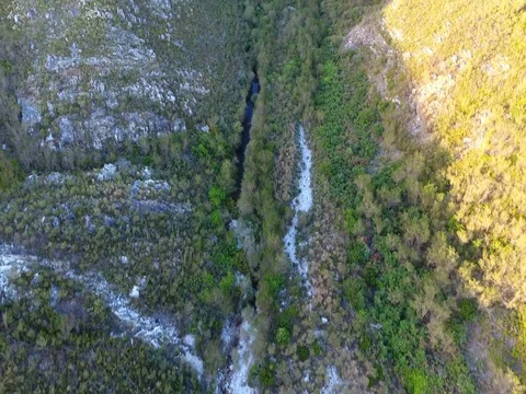 Drone follows river up towards massive ravine in Hermanus 스톡 동영상 79709539