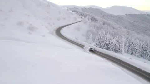 Drone follows silver SUV speeding uphill on steep mountain road in winter Video stock 168734443