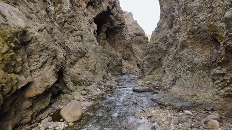 Drone follows stream into cliffs and crashes against the stone wall Stock Footage 128471302