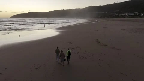 Drone follows three men walking along the beach at sunset Stock Footage 326678136