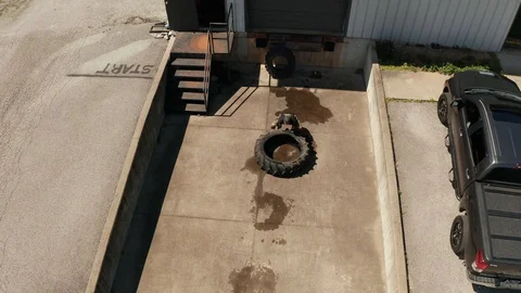 Drone Footage of an Athlete training flipping a tire Stock Footage 127982224