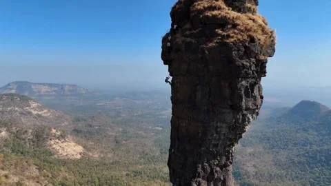 Drone Footage of a Boy Rappelling Down a Brown Cliff Between Mountains and Sky Stock Footage 287916068