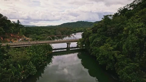Drone footage of bridge and the river below and the jungle around Stockbeeldmateriaal 244347076
