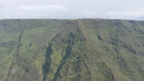Drone footage captures a dramatic aerial view of steep green cliffs topped with Stock Footage 346722016