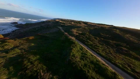 Drone footage captures dramatic coastline with grassy ridges and ocean waves Stock Footage 344577404