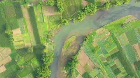 Drone footage captures a lush patchwork of agricultural fields and a winding Stock Footage 346665380