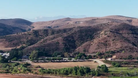 Drone footage captures rolling brown hills and a patch of greenery with Stock Footage 319464087