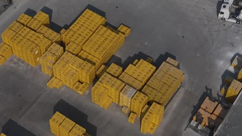 Drone footage captures vast stacks of yellow-wrapped goods and large trucks.. Stock Footage 331851105