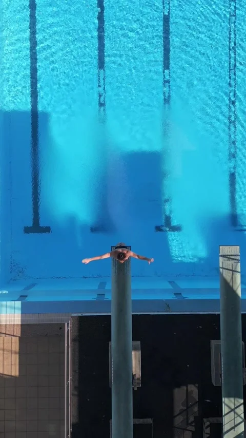 Drone footage capturing a diver mid-air performing a tuck dive above a clear Stock Footage 282291473