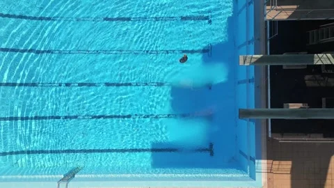 Drone footage capturing a diver mid-air performing a tuck dive above a clear Stock Footage 282295699