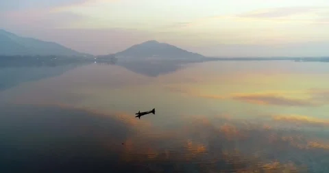 Drone footage capturing golden reflections around a boat on Dal Lake during Stock Footage 310656584