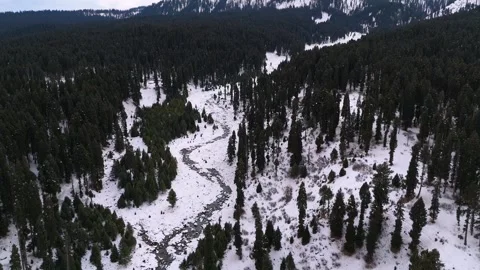 Drone footage capturing peaceful water flow through snow-clad Dhoodhpathri trees Stock Footage 311794045