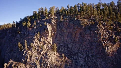 Drone footage capturing rugged cliff faces and isolated tree patches in New Stock Footage 332621719