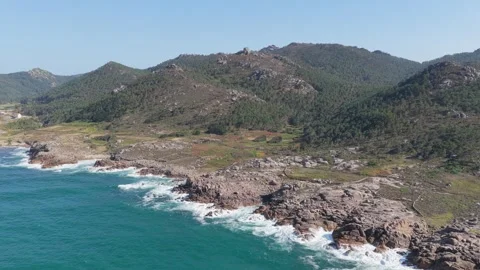 Drone footage capturing the rugged coastline and lush green hills of Praia de Stock Footage 346712773