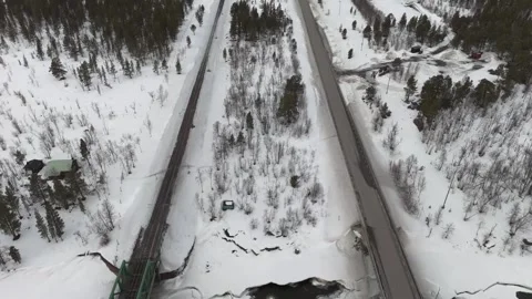 Drone footage capturing the stark, snowy landscape intersected by a road and Stock Footage 330376739
