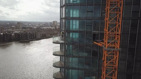 Drone footage of construction workers at height working on a glass skyscraper. Video stock 87869701